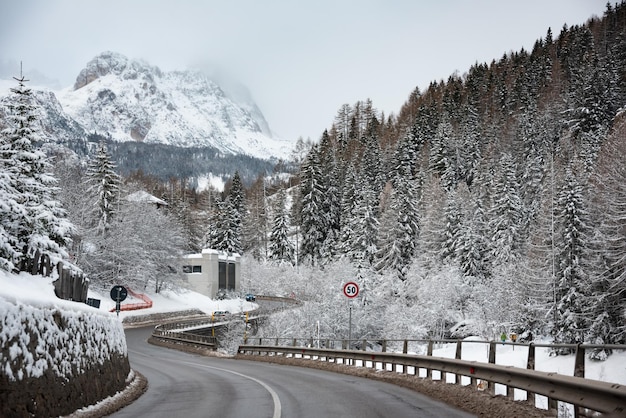 Estrada de inverno entre florestas nas montanhas Dolomitas, Itália.