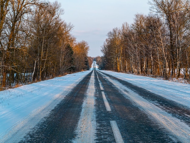 Estrada de inverno na neve saindo do horizonte da floresta