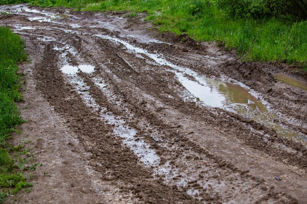 Estrada de lama de barro sujo com poças e trilhas de pneus fechadas com foco seletivo e perspectiva linear