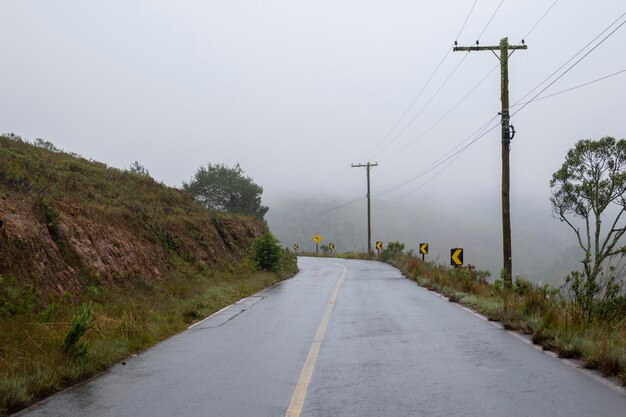 Estrada de mão dupla na área rural com árvores em dia de neblina. Nenhum carro