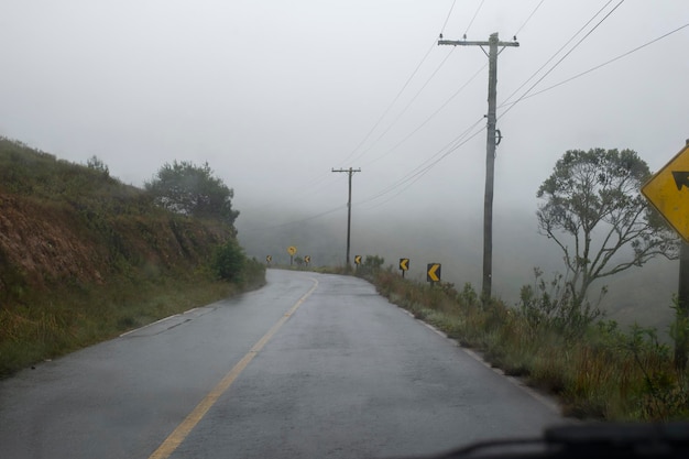 Estrada de mão dupla na área rural com árvores em dia de neblina. Nenhum carro
