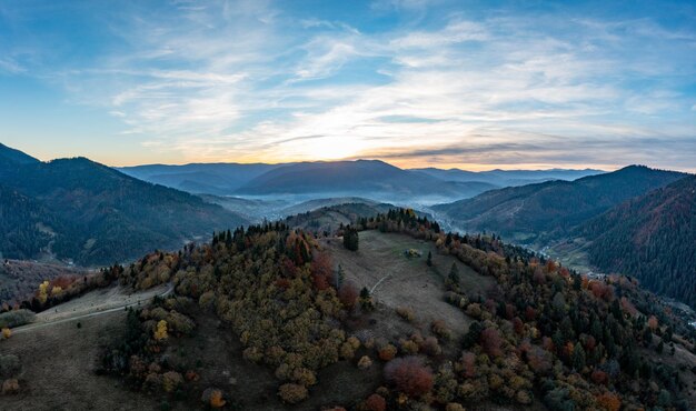 Estrada de terra em altas montanhas com floresta verde ao nascer do sol