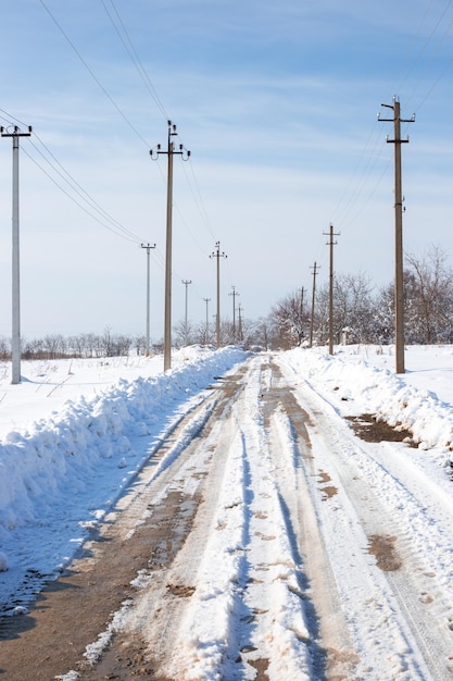 Estrada de terra rural com neve fresca limpa e postes elétricos ao longo da estrada