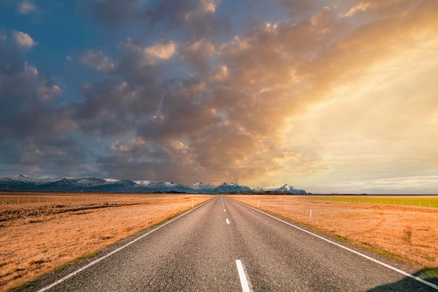 Estrada decrescente vazia em meio a paisagem vulcânica contra o céu durante o pôr do sol