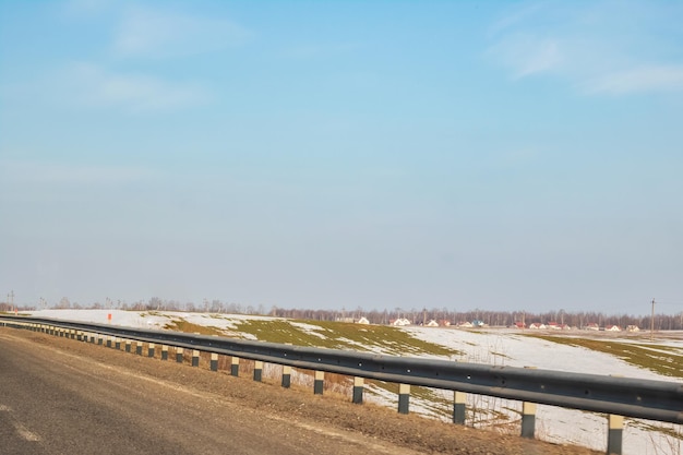 Estrada e campo com paisagem ensolarada de neve derretida