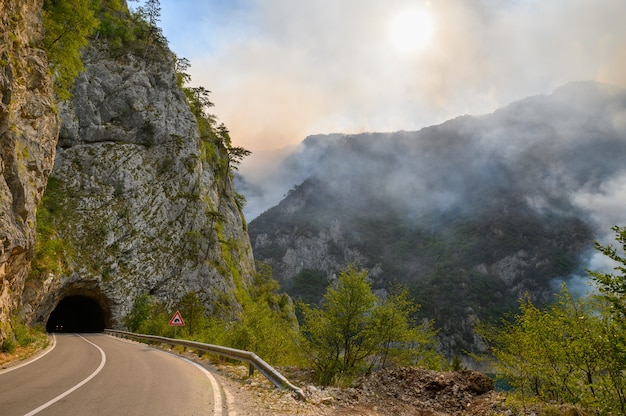 Estrada e túnel no lago piva no parque nacional dormitor de montenegro durante um incêndio no final de s ...