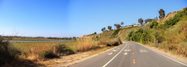 Foto estrada em meio a uma paisagem contra um céu azul claro