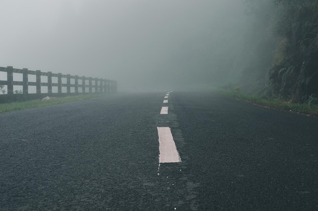 Estrada inclinada da estrada através de altas montanhas em um denso nevoeiro Névoa por nuvens em estações chuvosas