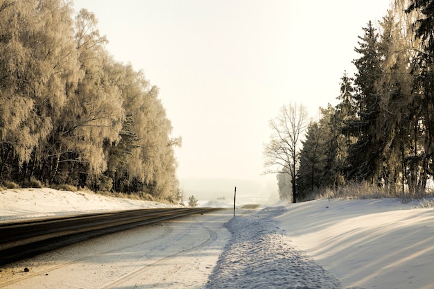 Estrada larga pavimentada de inverno coberta de neve após as quedas de neve de inverno, parte perigosa e difícil do caminho para o inverno gelado