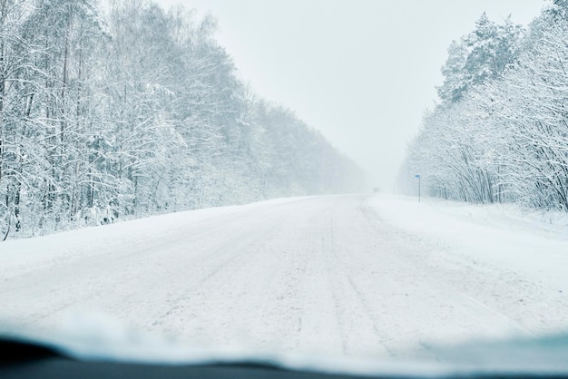 Estrada nevada na floresta de inverno com carro em movimento