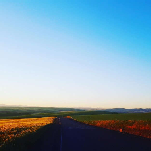 Foto estrada no meio do campo contra o céu azul claro