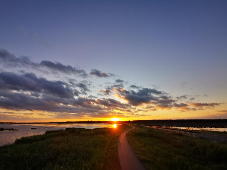 Foto estrada no meio do campo contra o céu durante o pôr do sol