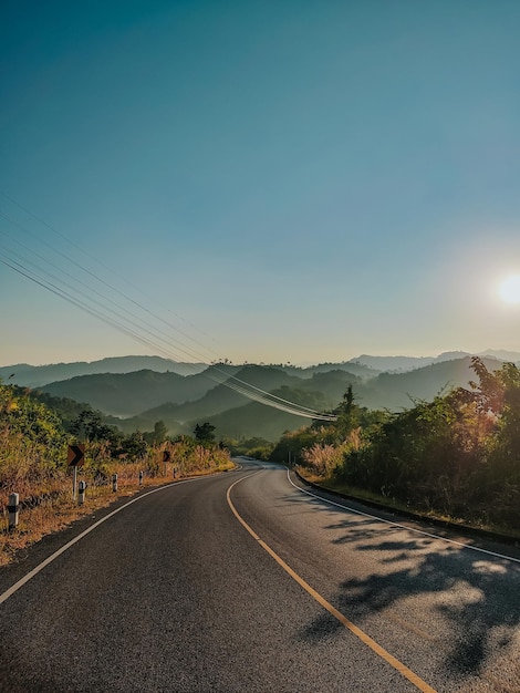 Foto estrada no meio do campo contra o céu durante o pôr do sol