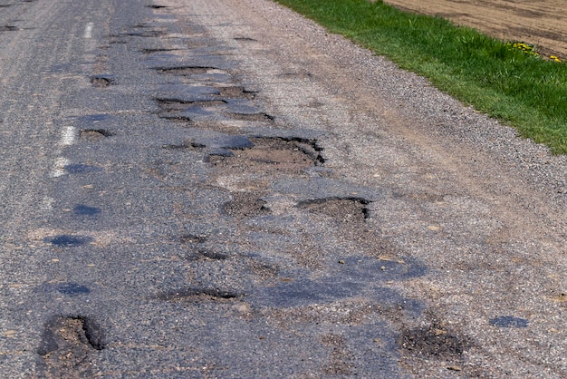 Estrada pavimentada pobre com muitos buracos e buracos