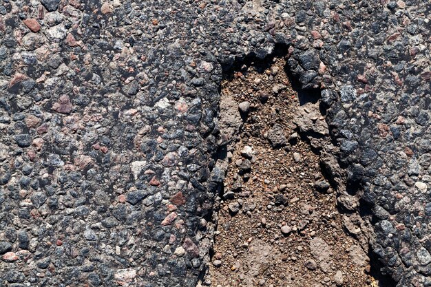 Estrada pavimentada, um close-up de uma parte da faixa de rodagem de uma estrada de asfalto, uma estrada feita de pedra britada, resina e outros materiais de construção