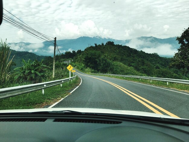 Estrada por montanhas contra o céu visto através do pára-brisas do carro