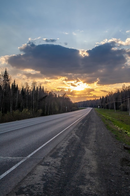 Estrada rural com marcações no meio da floresta Caminho e movimento para a frente no pôr do sol