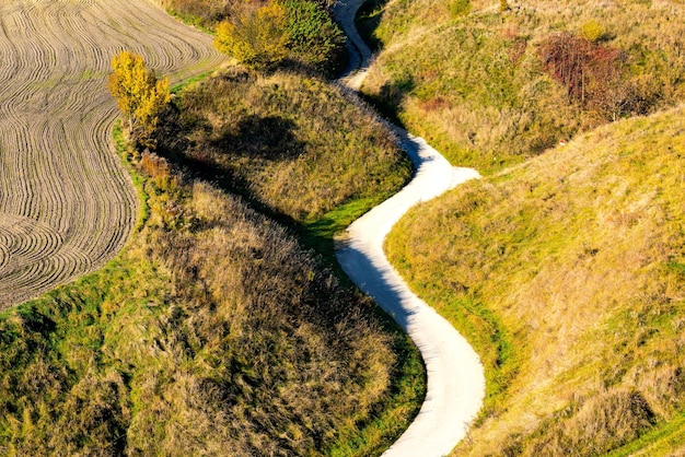 Estrada rural sinuosa nas cores da temporada de outono da Polônia rural na folhagem