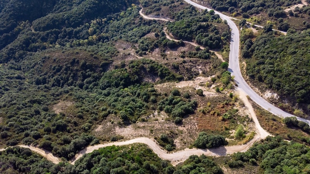 Estrada sinuosa, colinas cobertas por uma vegetação exuberante, vista do drone, Grécia