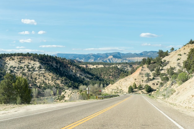 Estrada solitária entre cumes de montanhas com algumas árvores em cada lado da estrada em algum lugar em Utah, Estados Unidos