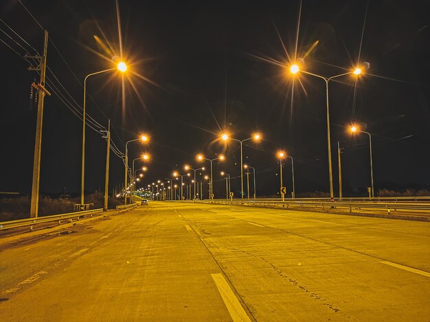 Estrada vazia contra luzes de rua iluminadas na cidade à noite