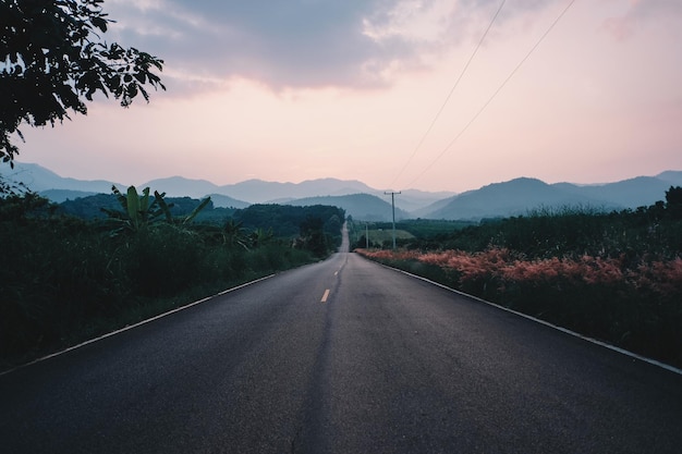 Estrada vazia contra o céu durante o pôr do sol