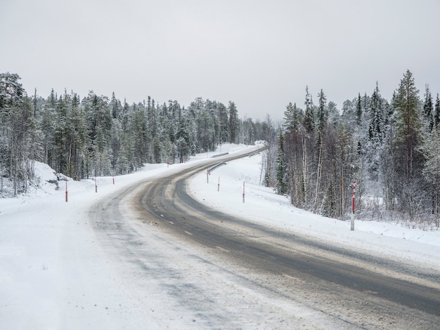 Estrada vazia do inverno nevado do Norte, vire na estrada.