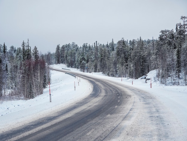 Estrada vazia do inverno nevado do Norte, vire na estrada.