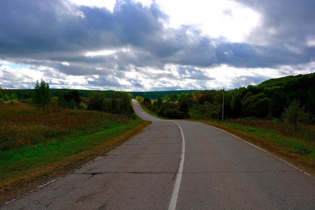 Estrada vazia no meio de um campo contra um céu nublado ao anoitecer