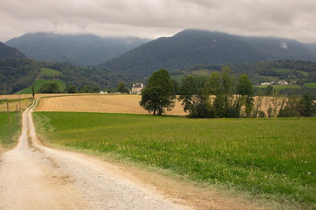 Estrada vazia rural em campos. Paisagem do Caminho de Santiago. Prado perto de montanhas em dia nublado.