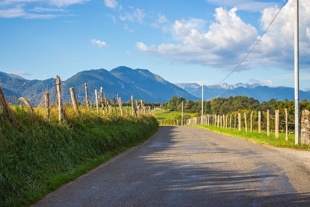 Estrada vazia rural em campos. Paisagem do Caminho de Santiago. Prado perto de montanhas em dia nublado.