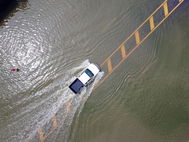 Estradas inundadas, pessoas com carros passando. Fotografias aéreas de drones mostram ruas inundando e carros de pessoas passando, espirrando água.