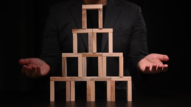 Estratégia de negócios e conceito de desenvolvimento. Empresário com bloco de madeira em quarto escuro.