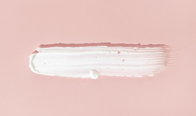 Foto estrecha de crema cosmética blanca aislada sobre fondo rosado producto para el cuidado de la piel
