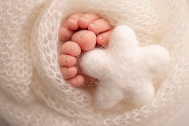 Estrela branca de malha nas pernas de um bebê pés macios de um recém-nascido em um cobertor de lã branco closeup de calcanhares e pés de um recém-nascido macrofotografia o pezinho de um bebê recém-nascido