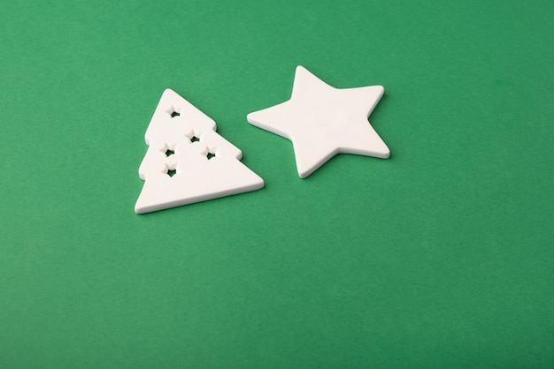Estrela branca e árvore de Natal feita de cerâmica em um fundo verde profundo