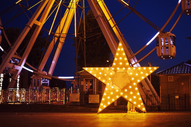 Estrela brilhante iluminada no parque de diversões na cidade à noite
