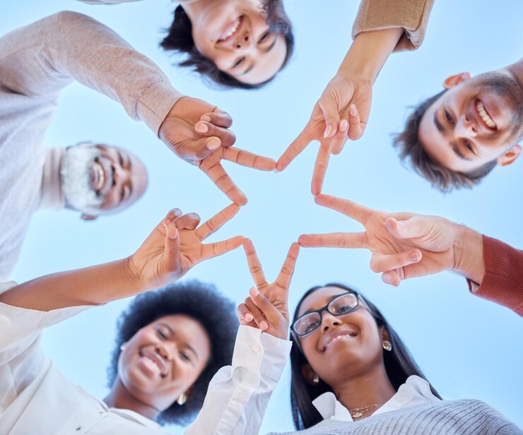 Foto estrela de baixo ângulo ou equipe feliz com diversidade de sinal de paz ou colaboração comunitária com céu azul sorriso de retrato ou grupo de pessoas sorrindo com solidariedade de apoio ou motivação juntos ao ar livre