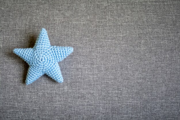 Estrela de malha azul em um fundo cinza têxtil