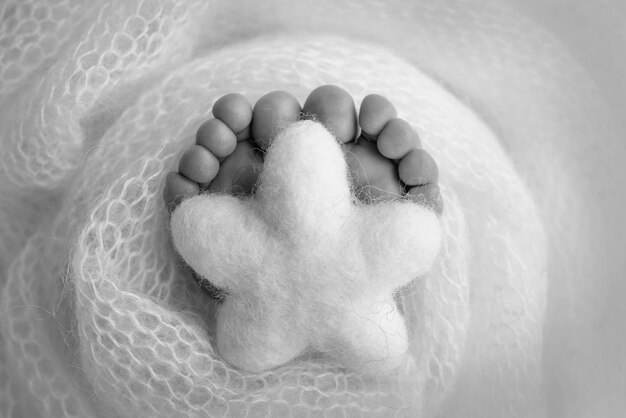 Estrela de malha nas pernas de um bebê Pés macios de um recém-nascido em um cobertor de lã Closeup de calcanhares e pés de um recém-nascido Fotografia macro em preto e branco o pezinho de um bebê recém-nascido