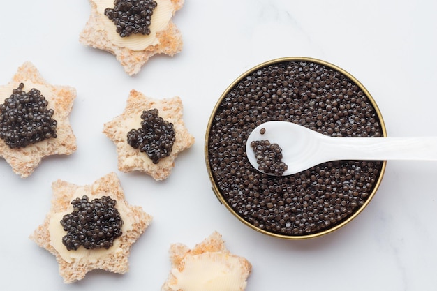 Estrela de pão de aperitivos de caviar preto em uma vista superior de fundo branco