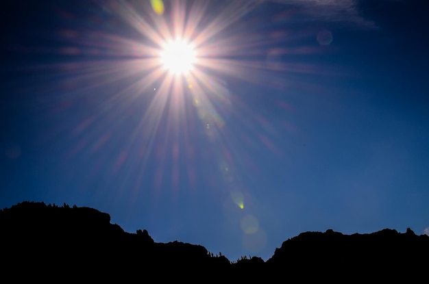 Estrela do sol em um céu azul sobre uma silhueta de montanha em Gran Canaria, Espanha