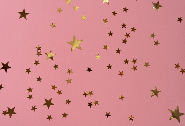 Foto estrelas douradas brilhando confete em fundo rosa cenário festivo de moda