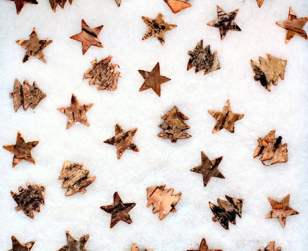 Estrelas e árvore de madeira do Natal no fundo da neve.