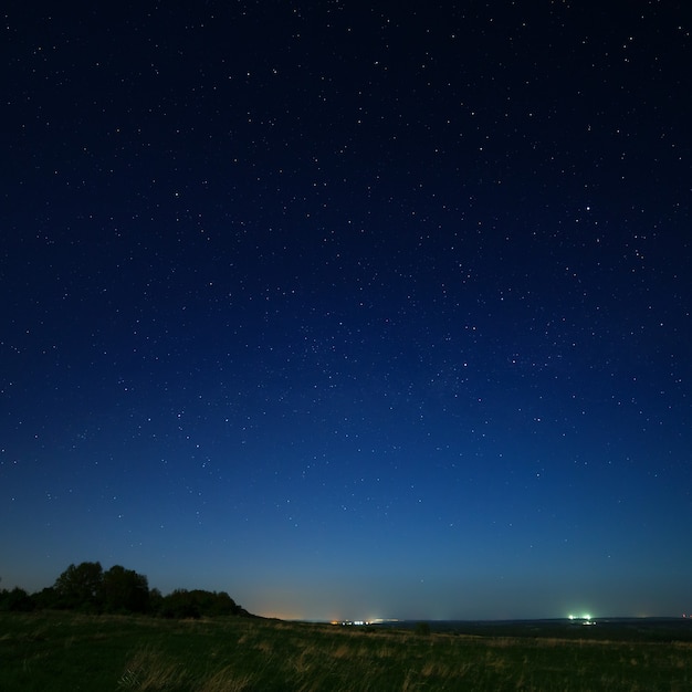 Estrelas no céu noturno com luzes da cidade no horizonte