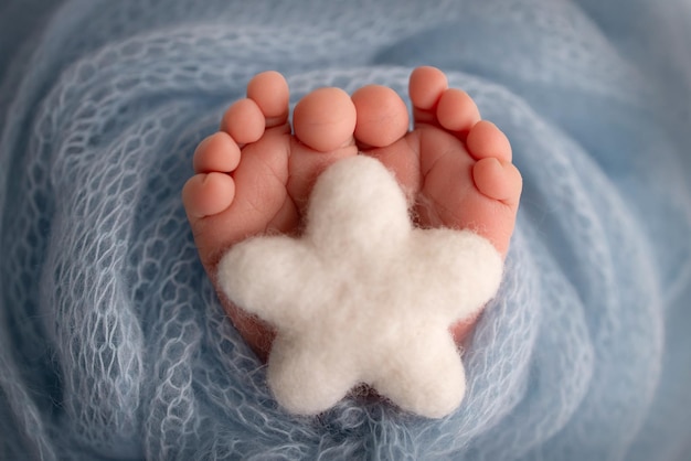 Estrella blanca tejida en las piernas de un bebé Pies suaves de un recién nacido en una manta de lana azul Primer plano de los talones de los pies y los pies de un recién nacido Fotografía macro del pie diminuto de un bebé recién nacido