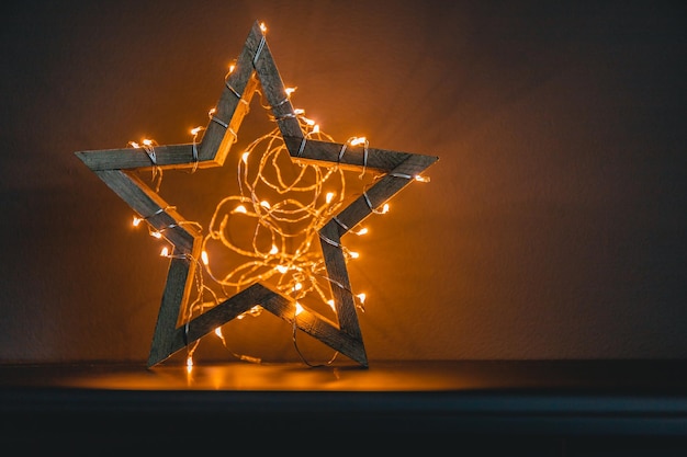 Foto estrella brillante de madera con un festón como símbolo de las vacaciones de año nuevo y el espacio de copia de navidad