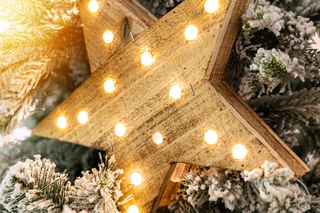Estrella decorativa de madera con lámparas colgando de ramas de pino