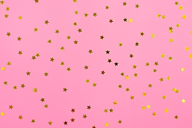 Foto la estrella dorada espolvorea en rosa. fondo festivo de vacaciones. concepto de celebración vista superior,