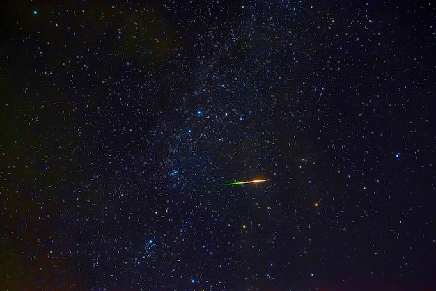 Estrella fugaz meteorito cometa sobre fondo azul oscuro cielo estrellado con galaxias y nebulosas